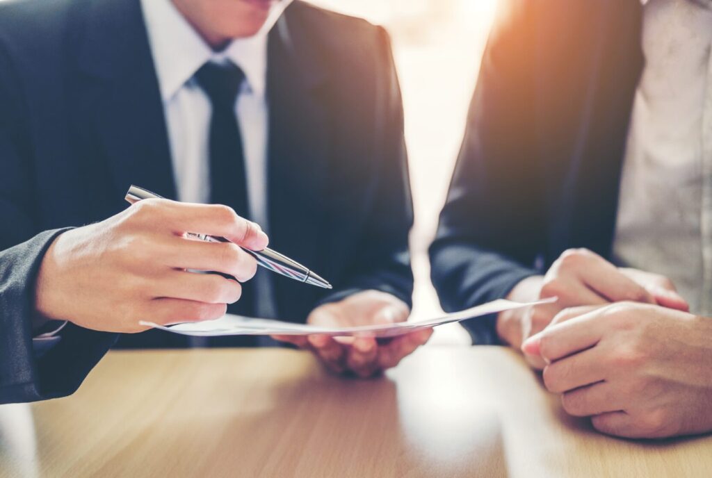 A close up of hands holding a pen and documents