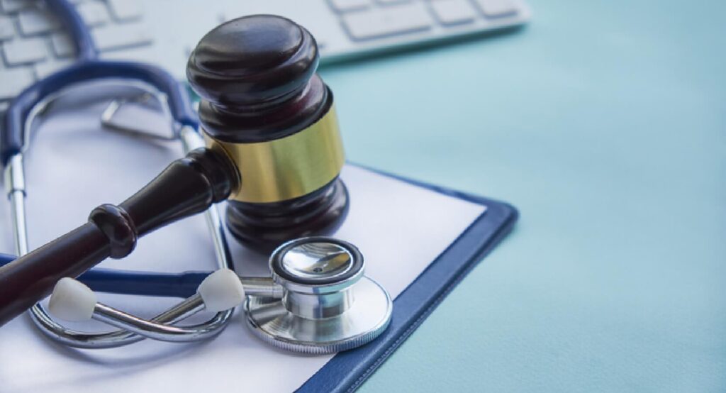 A gavel on a desk next to a stethoscope.