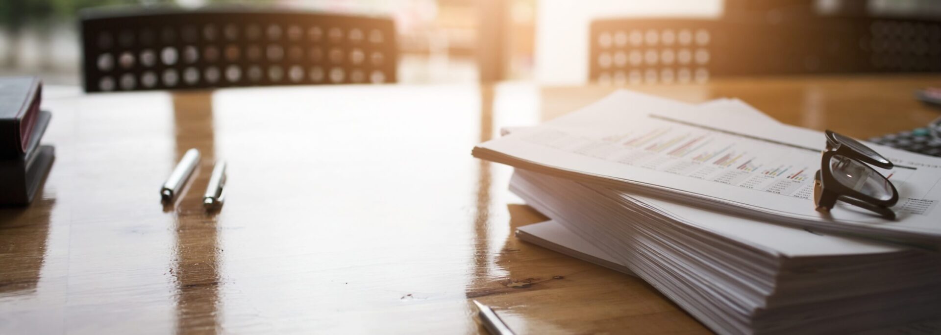 The sun reflects off a desk with a stack of papers.