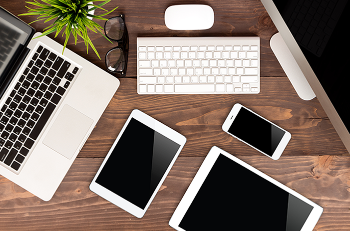 Various Apple devices on wooden desk.