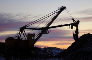 Mining equipment silhouette against sunset sky.