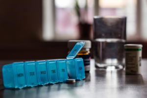 Pill organizer with medicine tablet and glass of water.