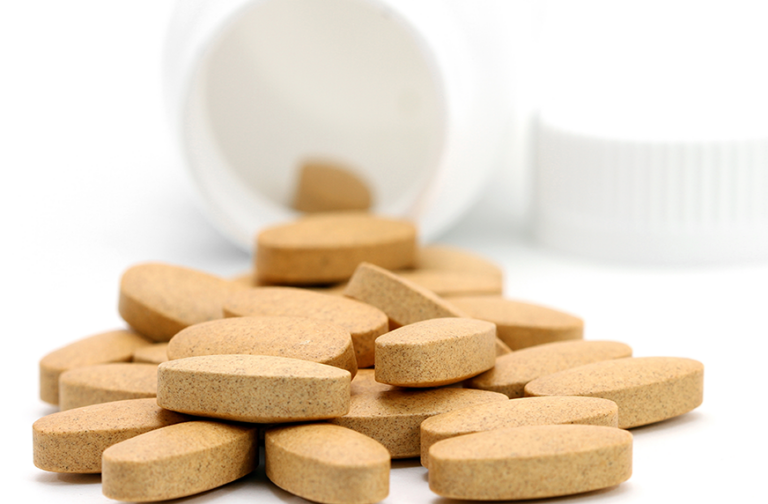 Vitamins spilling out of white bottle.